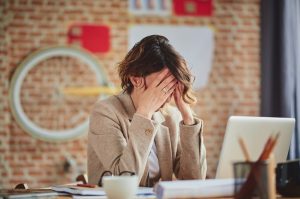 mujer trabajadora con ansiedad apoyándose la cabeza con las manos