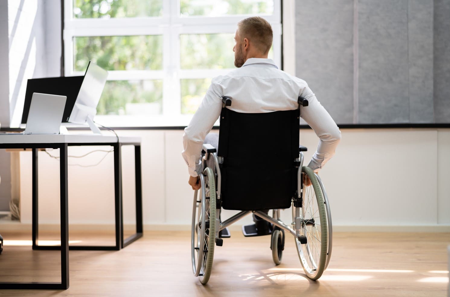 hombre sentado en silla de ruedas delante del escritorio de trabajo