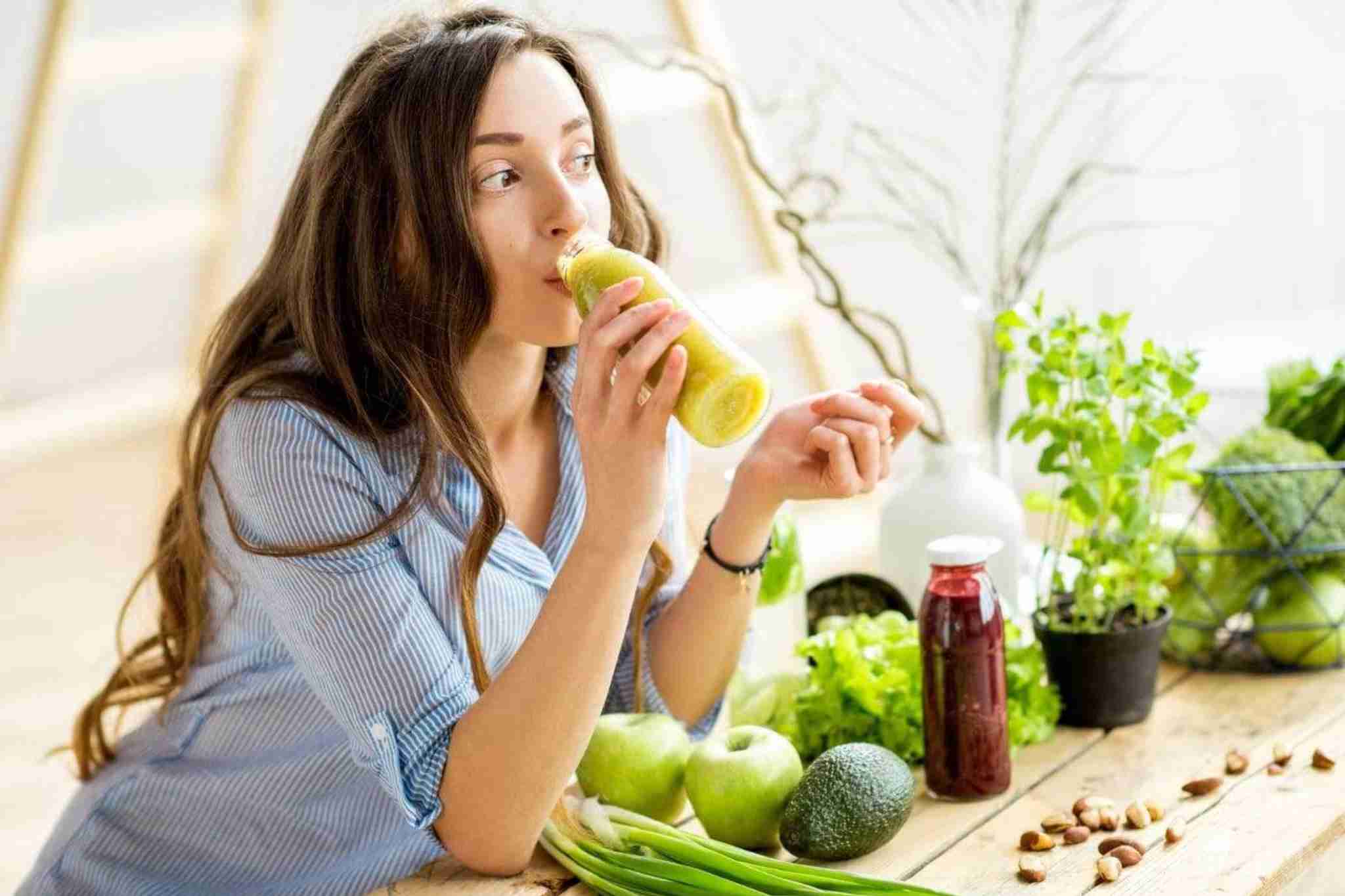 mujer joven bebiendo un zumo de verduras detox