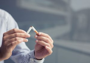 Persona rompiendo con sus manos un cigarrillo