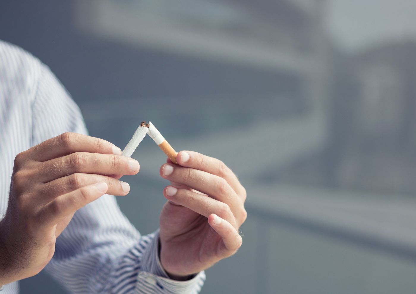 Persona rompiendo con sus manos un cigarrillo