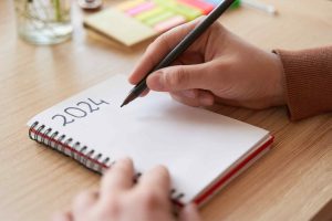 persona apuntando en libreta los nuevos propósitos para el año 2024