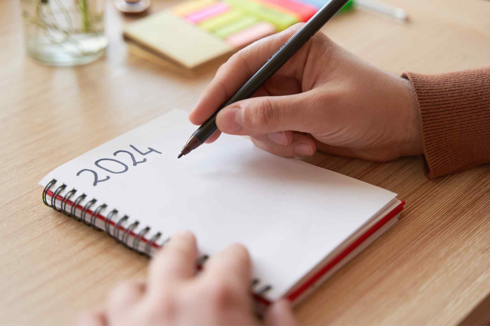 persona apuntando en libreta los nuevos propósitos para el año 2024
